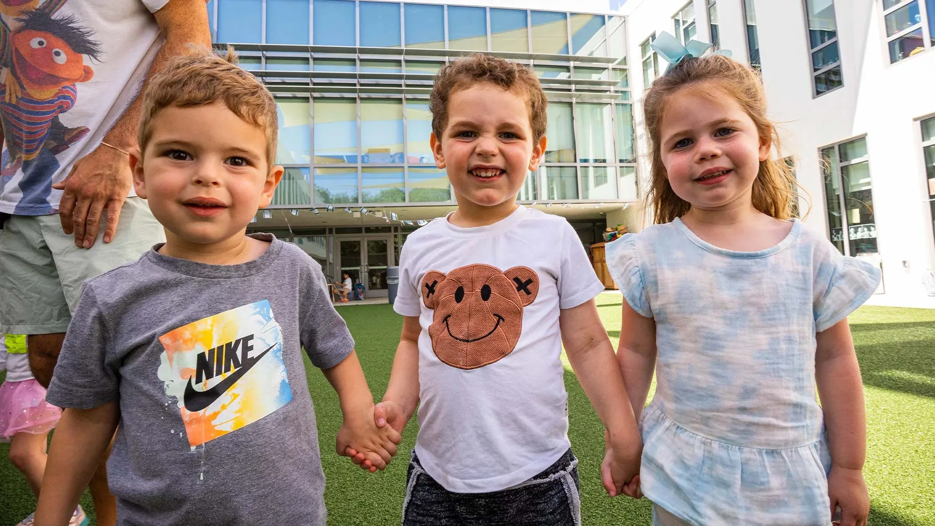 three young children playing in the outdoor courtyard after school