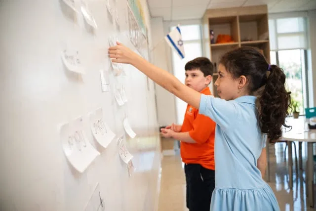 students remove post-its from a white board