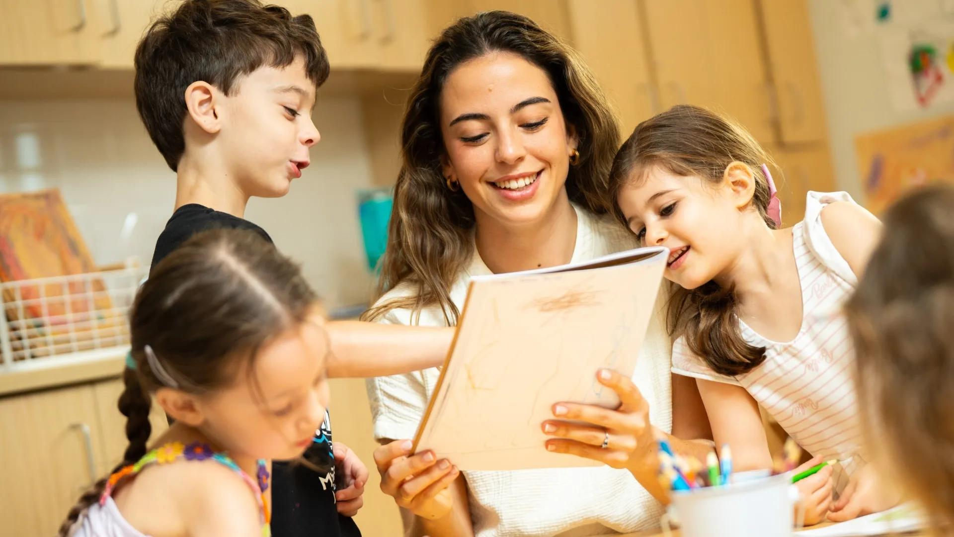 Early Childhood Associate Teacher looking at student's notebook