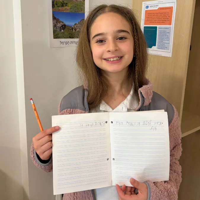young girl shares a notebook of hebrew