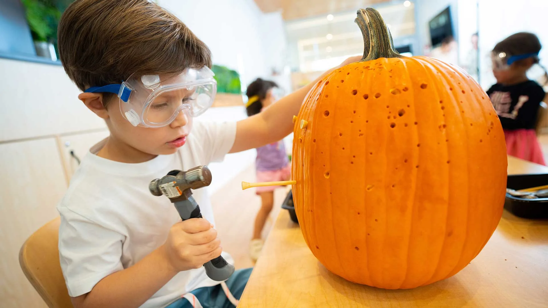 boy hammers golf tees into a pumpkin