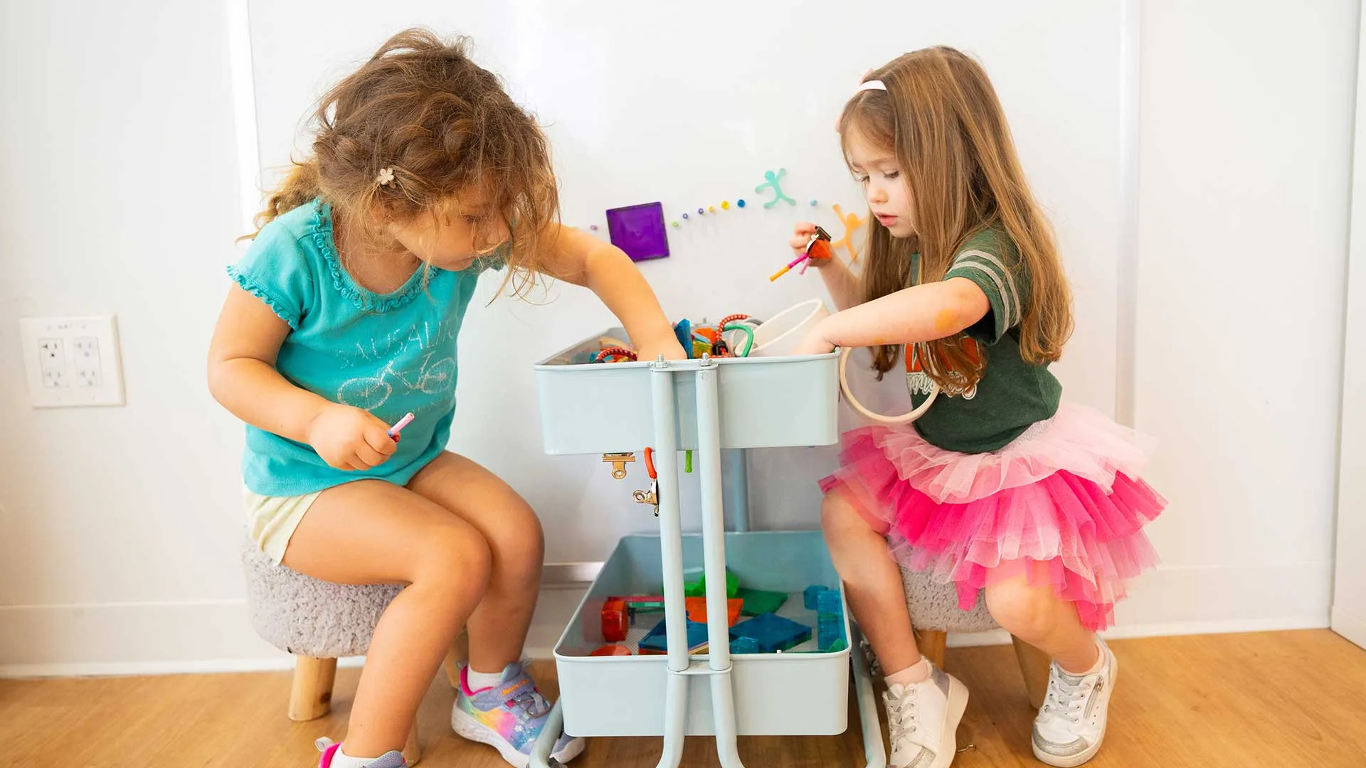 Two girls pick out items from a craft cart