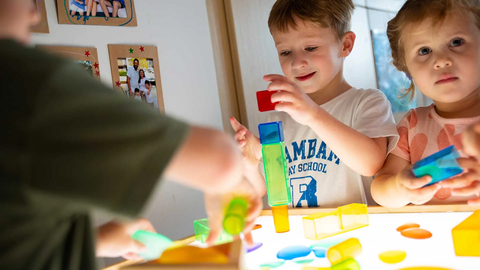 boy places plastic toys on a lightbox to illuminate the colored toys